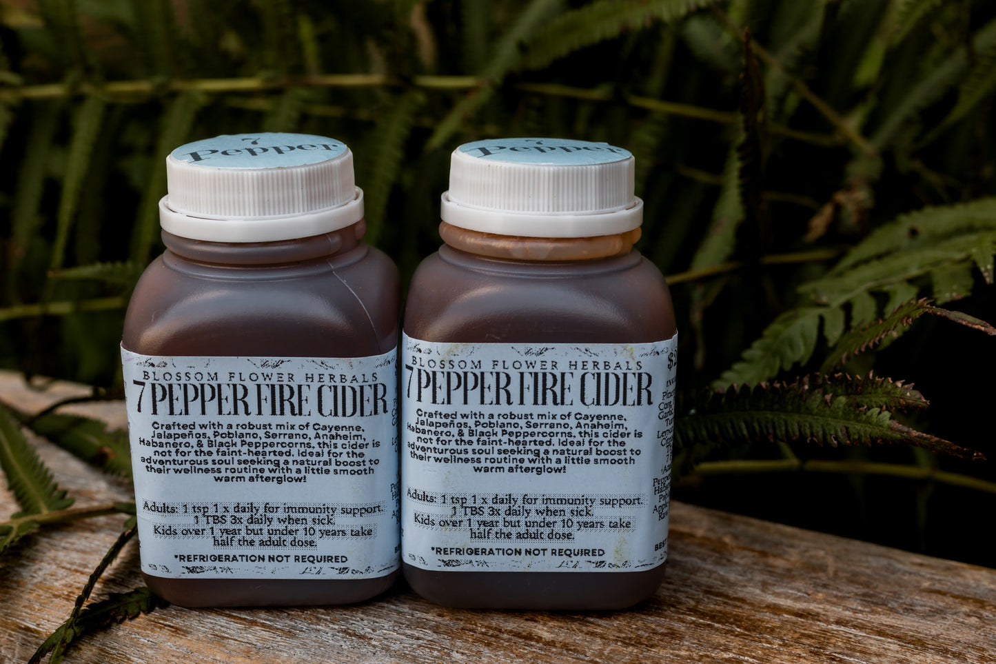 A vibrant bottle of 7 Pepper Fire Cider, showcasing a golden orange hue with flecks of rich red and earthy spices, representing its bold, zesty, and fiery flavor profile.